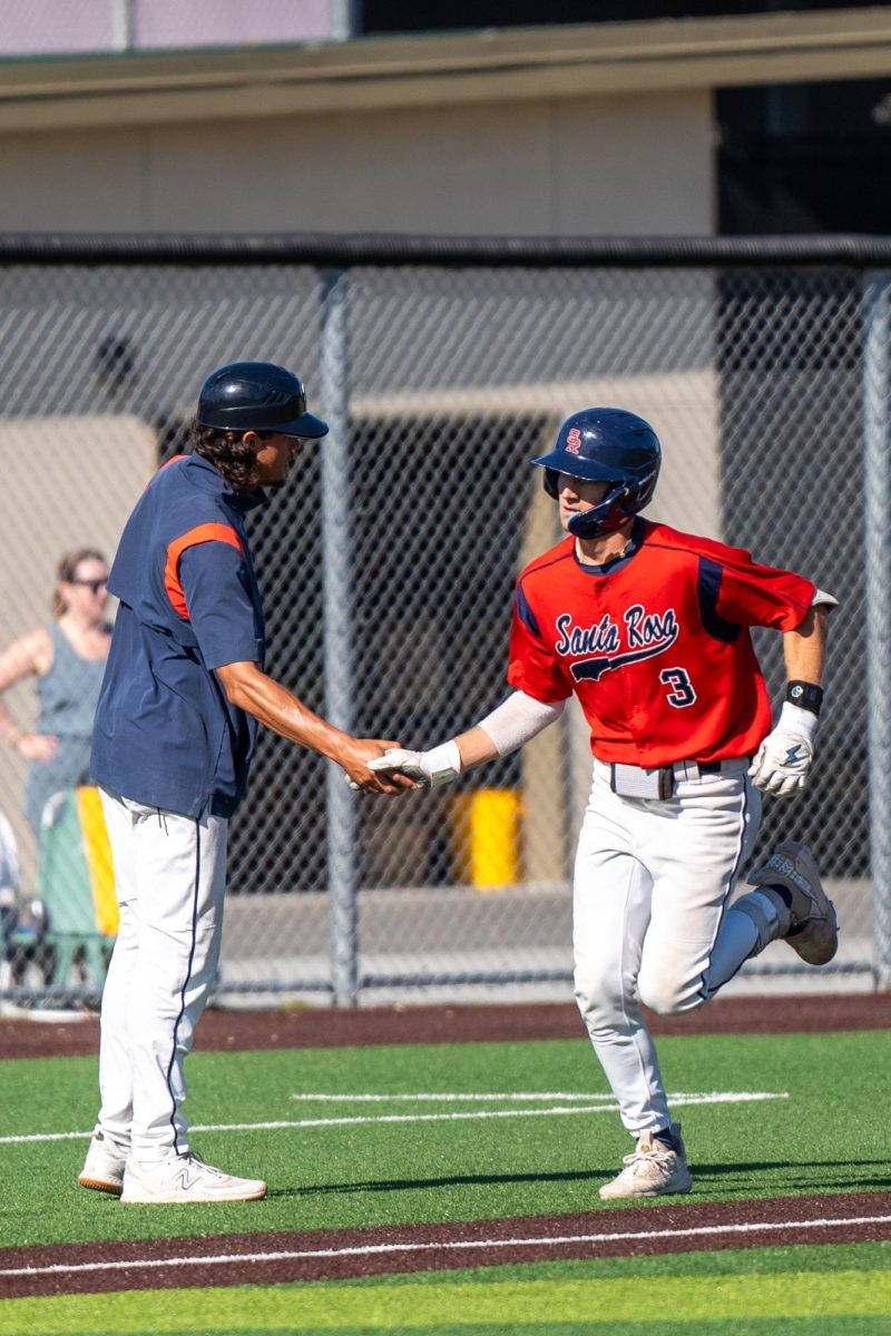 Shortstop Aidan Lombardi shakes third base coach Jeff Barts hand on his way to home plate after a home run in the bottom of the seventh secures two more runs against Chabot College in the second round of the CCCAA Super Regionals in Hayward on Thursday, May 9, 2024.