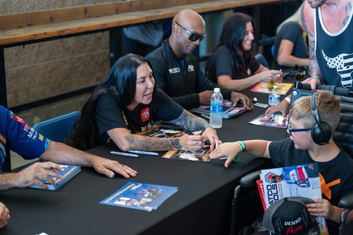 NHRA Funny Car driver Alexis DeJoria signs an autograph for a young fan at the DENSO NHRA Sonoma Nationals on Friday, July 26, 2024 in Sonoma.