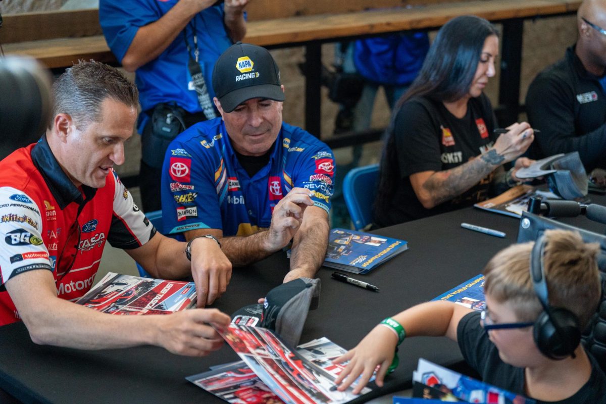 NHRA Funny Car Drivers Bob Tasca III, left, and Ron Capps sign autographs for kids at the DENSO NHRA Sonoma Nationals on Friday, July 26, 2024 in Sonoma.