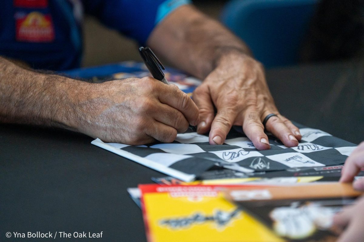 Funny Car driver Ron Capps autographs a sign for a fan at the DENSO NHRA Sonoma Nationals on Friday, July 26, 2024 in Sonoma.