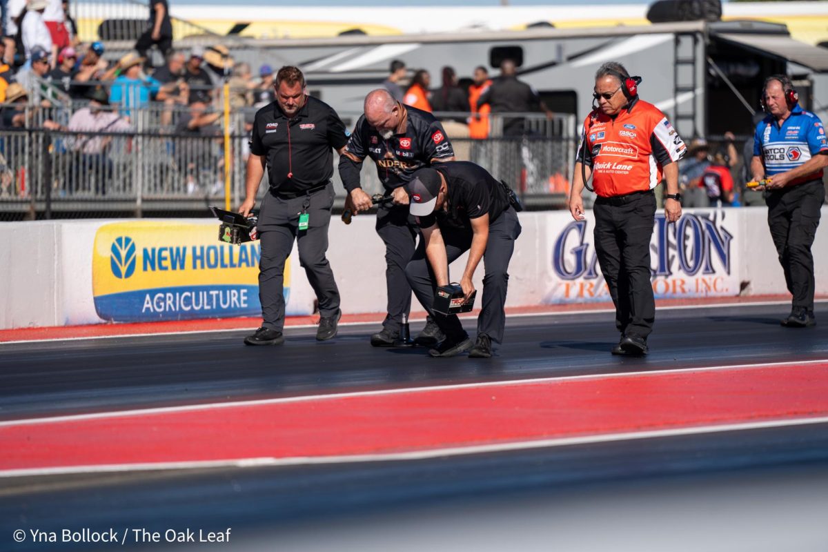 Pit crew members use a track meter and a traction measuring device prior to the Top Fuel runs to analyze the track at the DENSO NHRA Sonoma Nationals on Friday, July 26, 2024 in Sonoma.