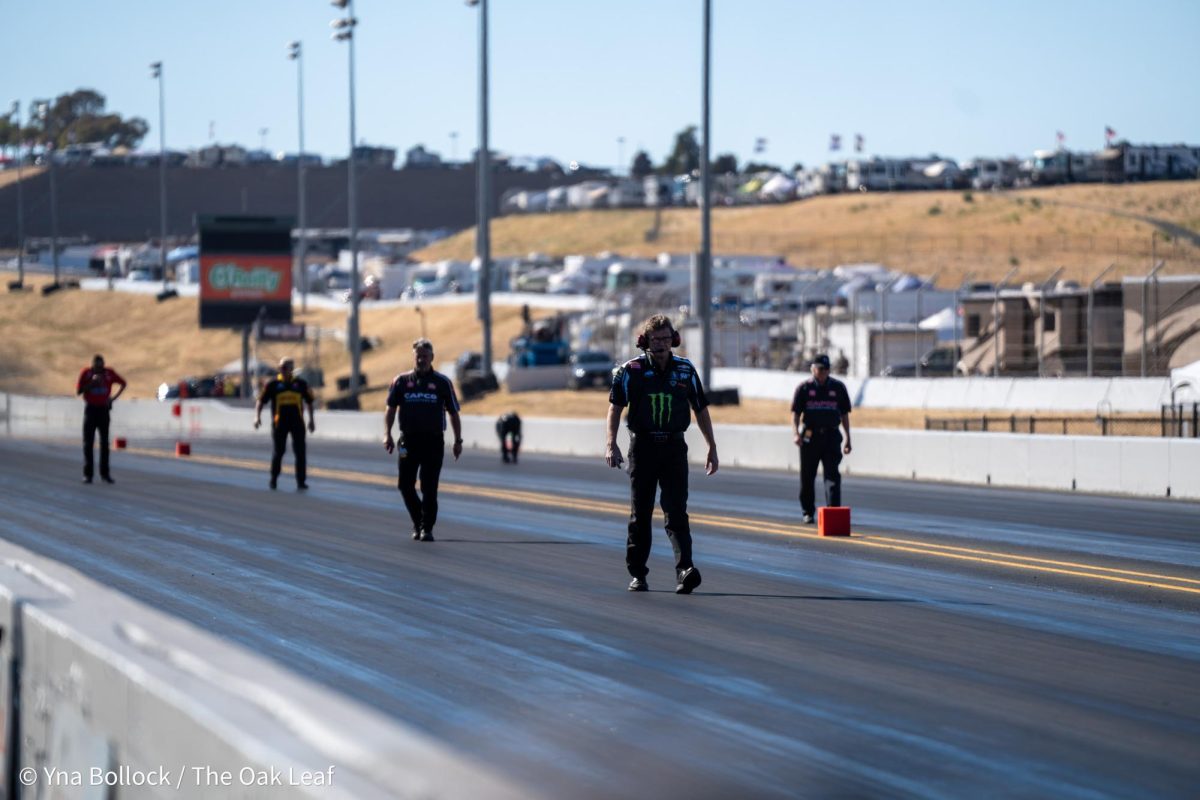 Pit crew members walk back to the starting line after analyzing the track prior to the Top Fuel runs at the DENSO NHRA Sonoma Nationals on Friday, July 26, 2024 in Sonoma.