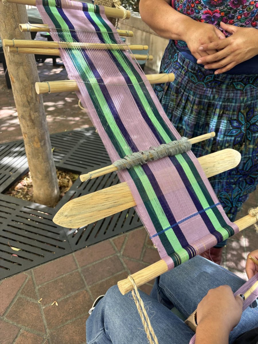 An attendees loom beginning to add designs with a thick needle and thread while Sari guiding them at Santa Rosa Junior College 20 Sept. 2024