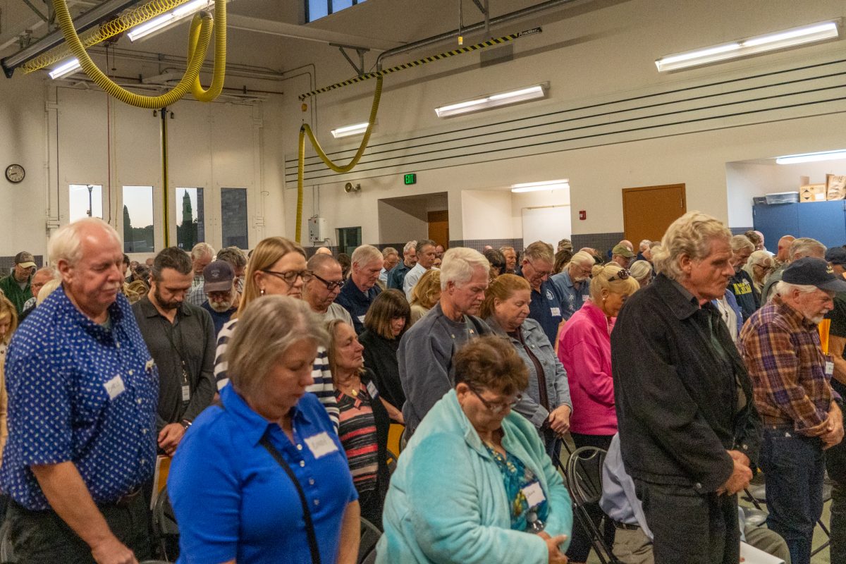 Attendees bow their heads to mourn the loss of former Fire Chief Doug Williams during State Senator Mike McGuire’s Town Hall Meeting in Windsor at the Sonoma County Fire District Station No. 3 on Oct. 17, 2024.