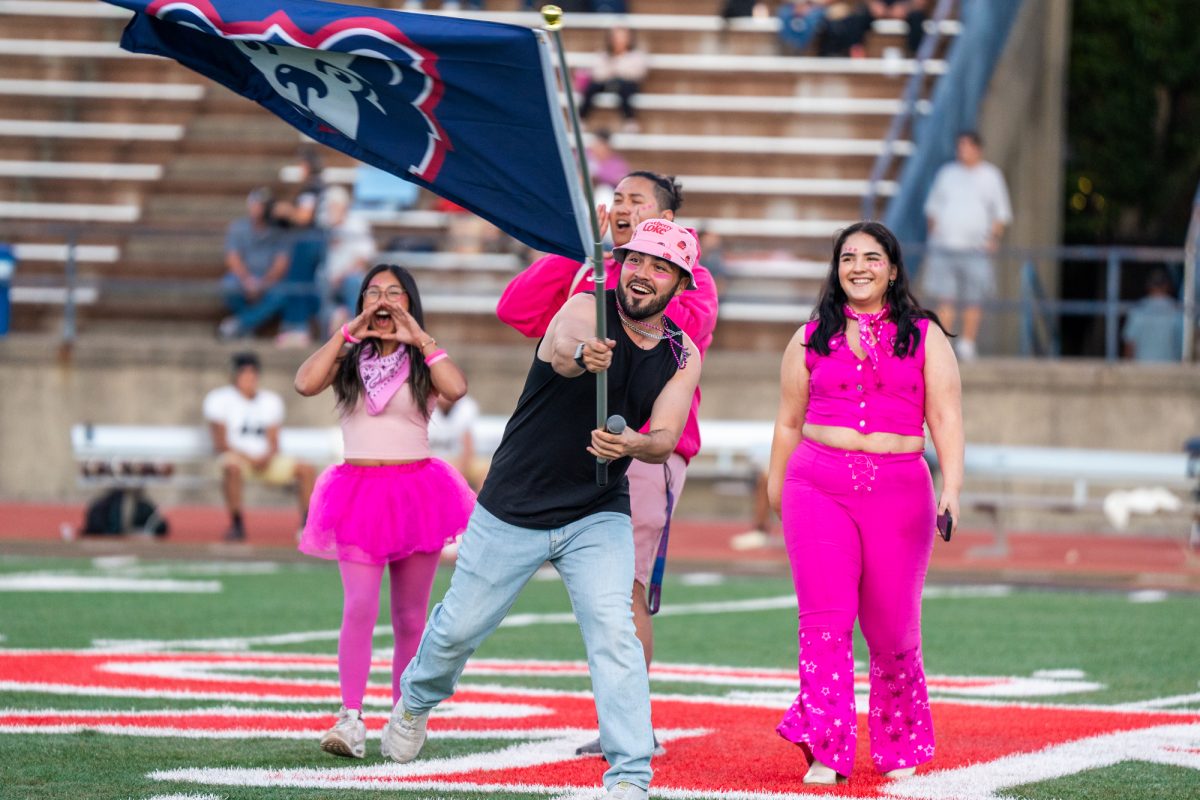 Members of the SGA Committee cheer and wave the school flag at halftime on the evening of the homecoming game against Butte College at home on Friday, Oct. 18, 2024.