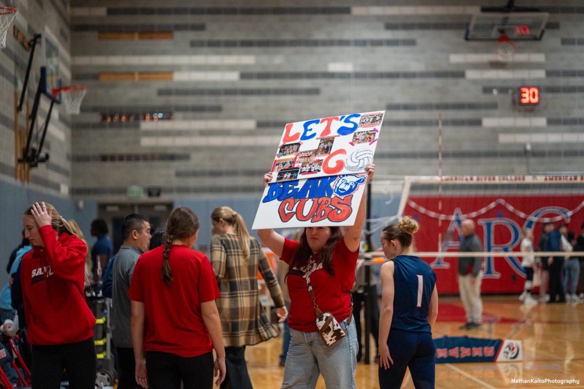 The traveling Bear Cub’s support holds up a sign reading, “Let’s Go Bear Cubs” with photos from throughout the season against American River at the American River gym on Tuesday, Nov. 26. 