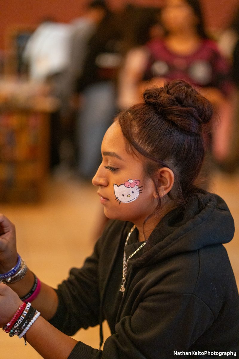 Areli Garcia applies face paint on an attendee of the Dia De Los Muertos festivities at the BertoliniStudent Center on Wednesday, Oct. 23.