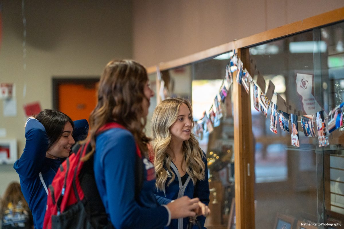 Stephanie Melendez, left, Katie Brenninger, center, and Sierra Yates-Bruch, right, view the photos from their season, on display at Haehl Pavilion before their game against San Joaquin Delta on Friday, Nov. 15, 2024.