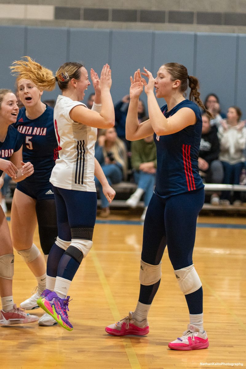 Bear Cubs’ defensive specialist Jaiden Brooner jumps to meet outside hitter Kaite Brenninger for a high-five against American River at the American River gym on Tuesday, Nov. 26. 