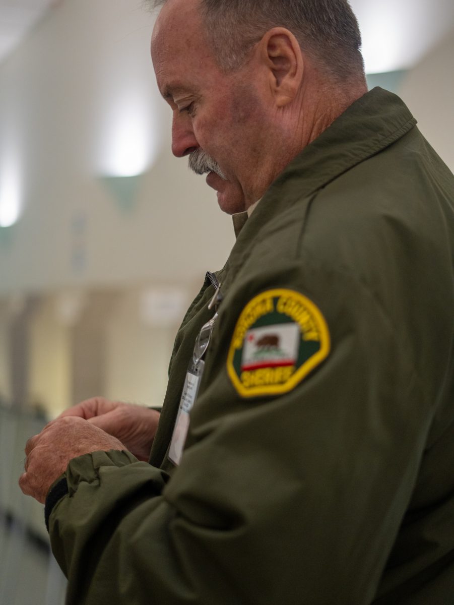 A sheriff peels an "I Voted" sticker for Oak Leaf Reporter Nathan Kaito Morris at the Registrar of Voters on Nov. 5th, 2024 