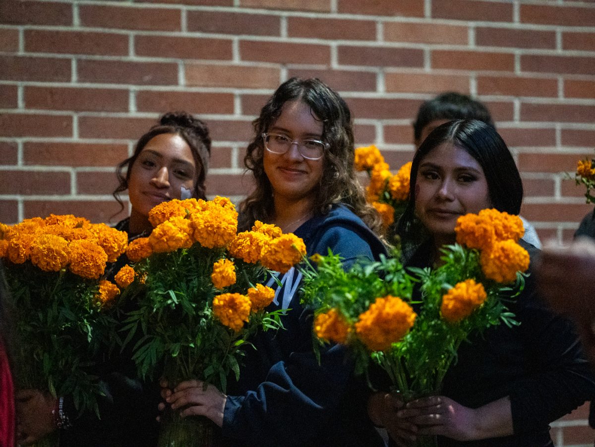 Marigolds are handed to attendees on their way into Newman Auditorium to view the first of many ofrendas during the Dia De Muertos celebration at the Santa Rosa campus on Wednesday, Oct. 23, 2024.