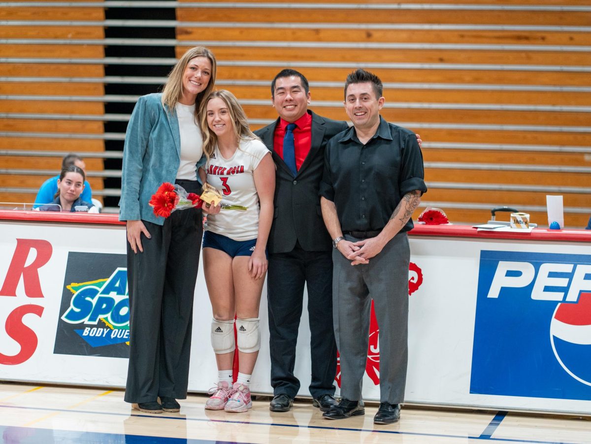 Setter Sierra Yates-Bruch poses with head coach Ally Sather, left, and assistant coaches, Tommy Wong, center, and Ryan Hughes, right, ahead of Sophomore Night at home against San Joaquin Delta on Friday, Nov. 15, 2024.