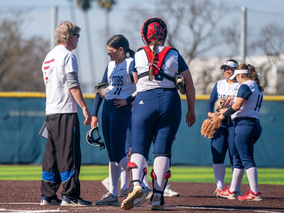 Assistant coach Doug Buescher meets with pitcher Mia Avila, center, at the top of the third in game one against Hartnell at home on Friday, Jan. 24, 2025.