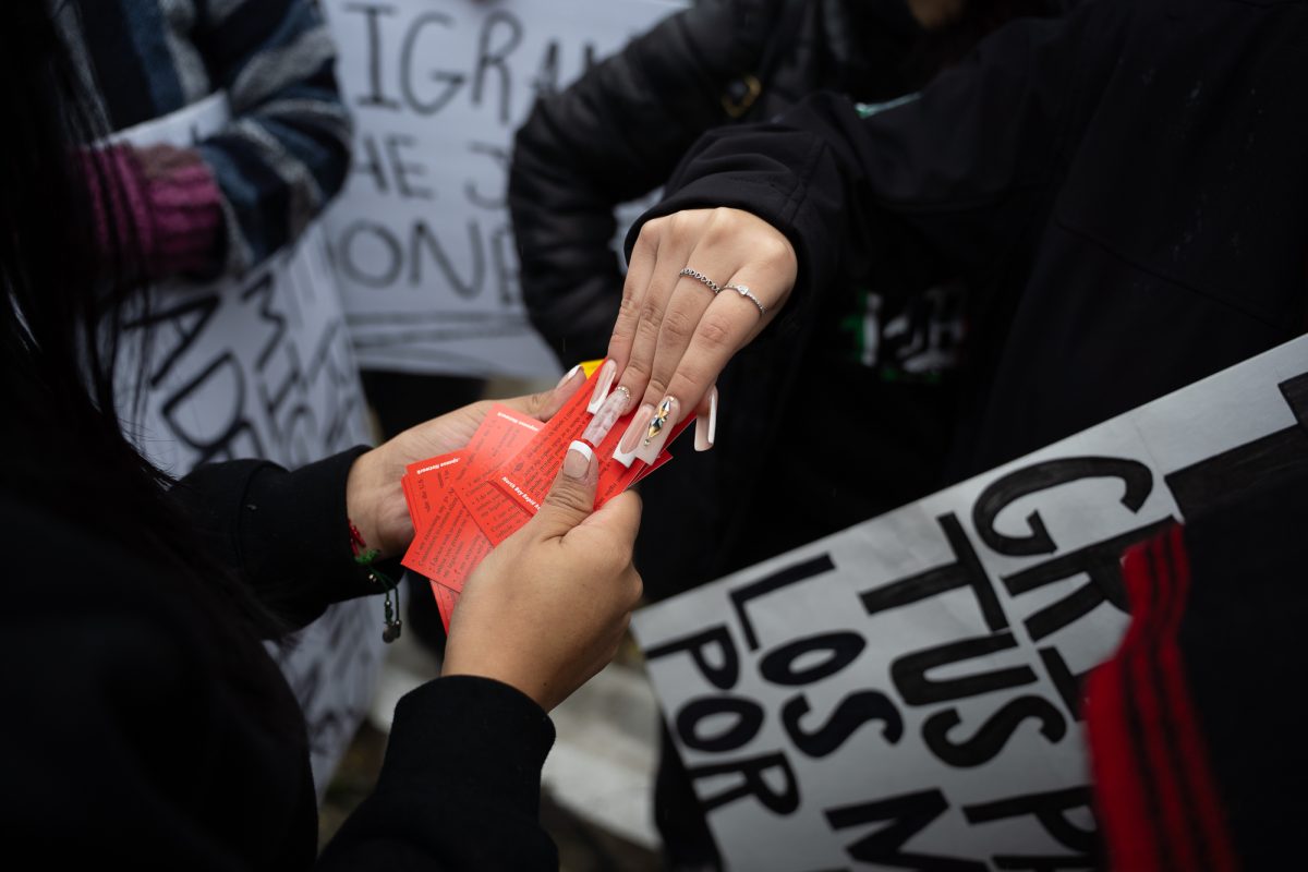 Protesters pass around cards outside of Mitote Park that can be slipped under a door in case of an ICE officer sitting outside someone's house; the card has information regarding fifth and fourth amendment rights.