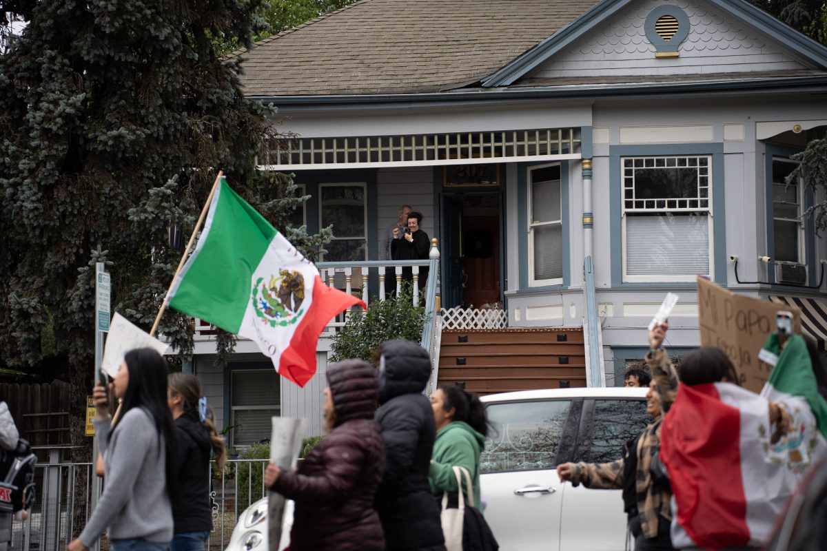 Onlookers come out of their homes to watch as protesters march down Olive Street on Monday, Feb. 3, 2025.