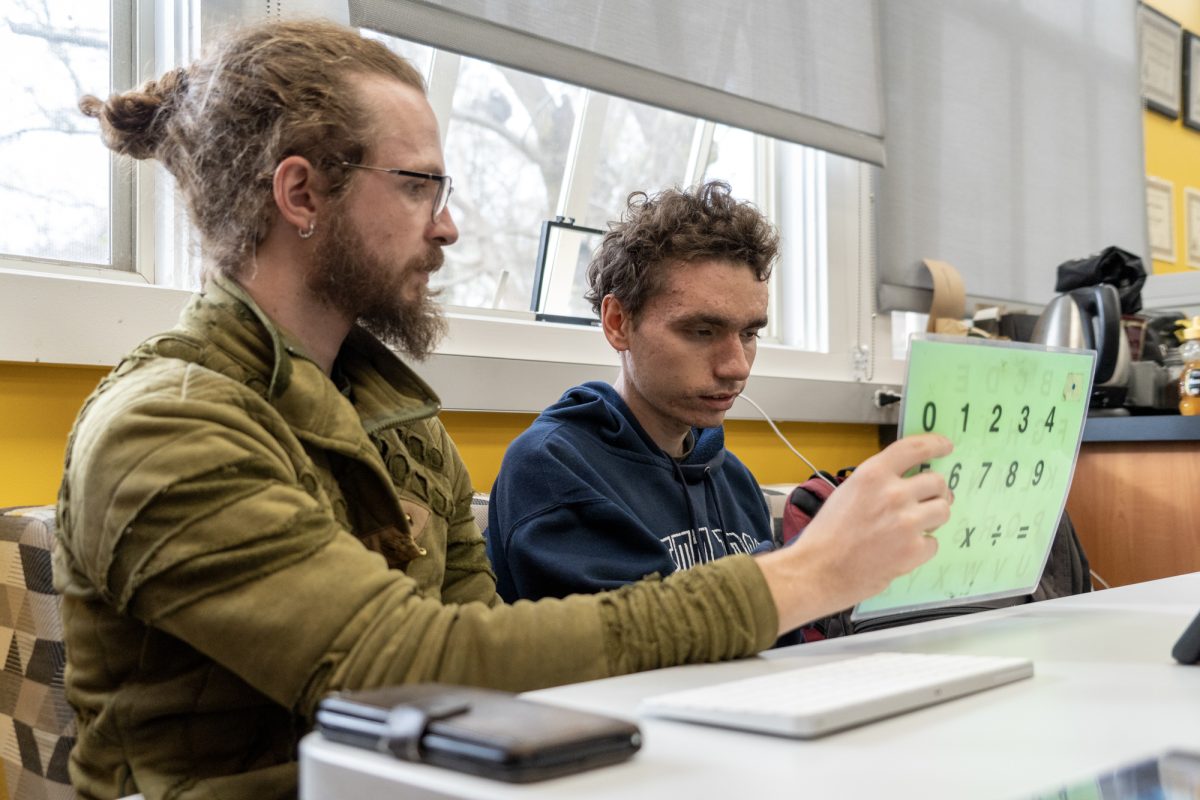 Noah McSweeney selects letters to ask a question of a guest speaker with the help of his communication partner Buckminster Barrett during an Oak Leaf class March 4, 2025.